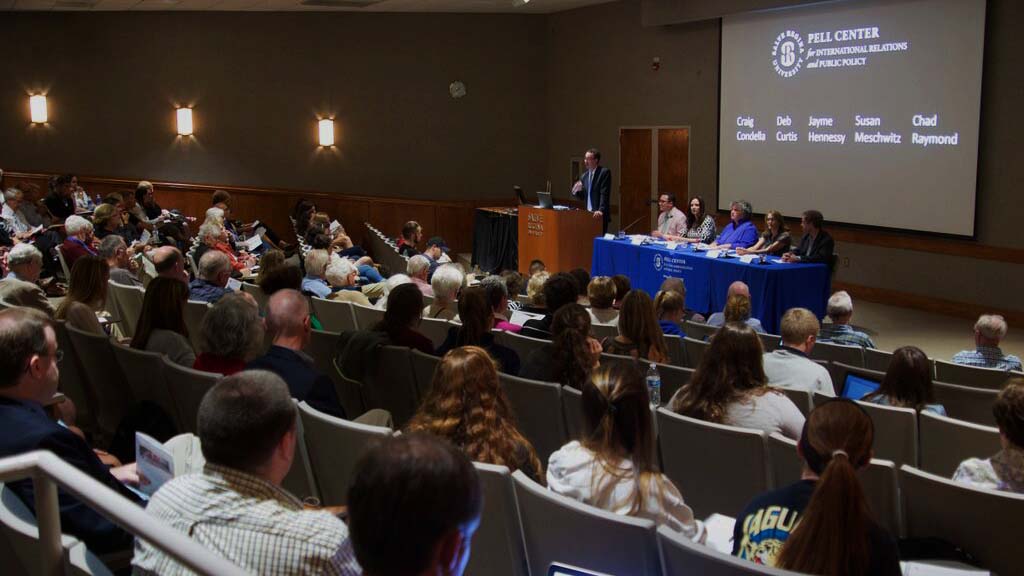 Pell Center Executive Director Jim Ludes moderates the lecture about Pope Francis' encyclical letter as panelists Craig Condella, Deb Curtis, Jayme Hennessy, Susan Meschwitz and Chad Raymond look out upon a crowd of Salve students and Newport community members