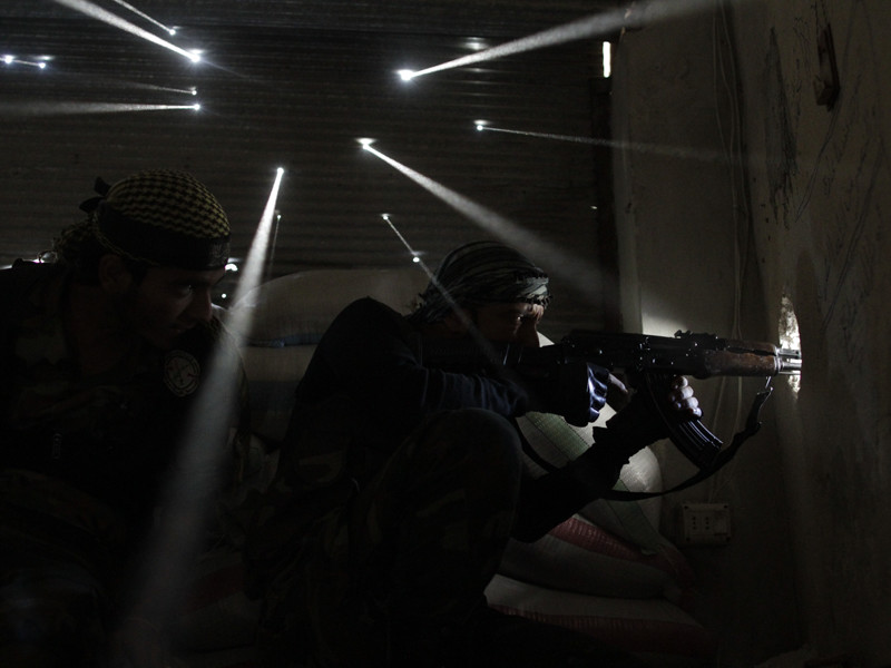 Pulitzer Prize winning image taken by Javier Manzano of Syrian rebel soldiers guarding their position as light streams through bullet holes in a wall.