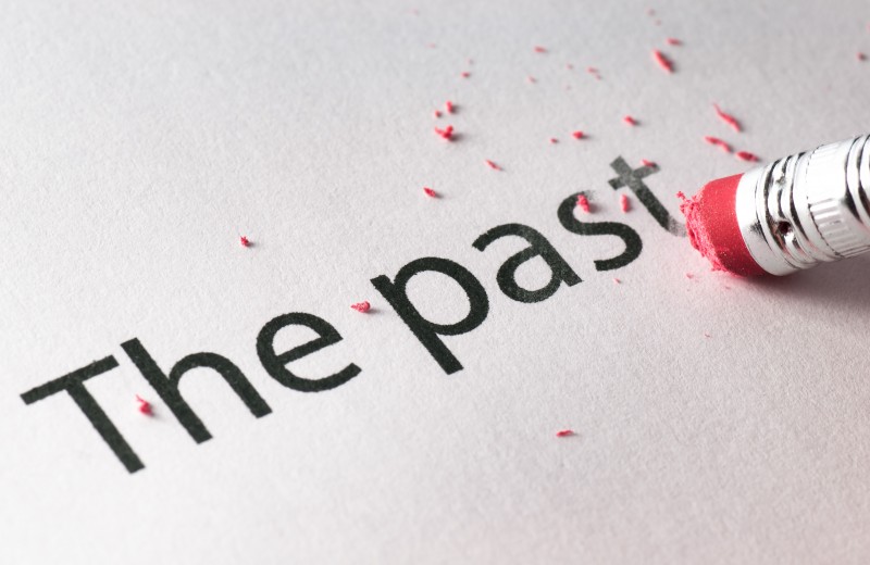 Pencil erasing the words "the past" from a white page.