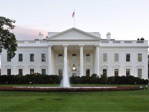 Image of the front of the White House and its fountain against gray skies.