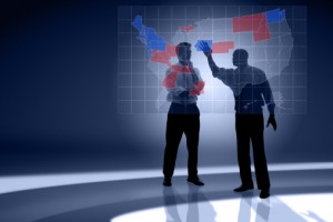 Two men ponder which states will end up Republican and Democratic in front of a map of the United States.