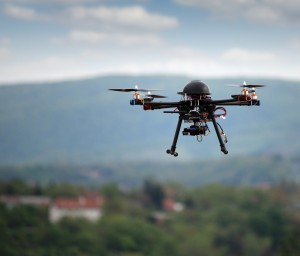 Image of a small drone helicopter with a camera on it flying through the sky