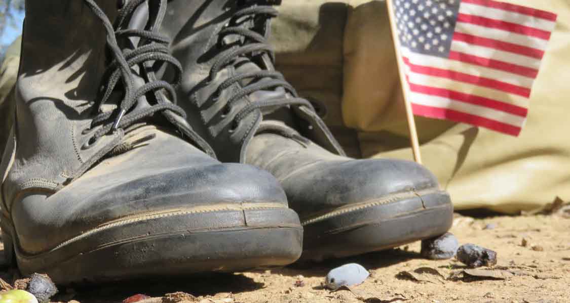Combat boots on the ground next to a small American Flag